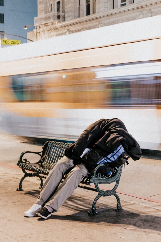 person sleeping on bench with passing train behind