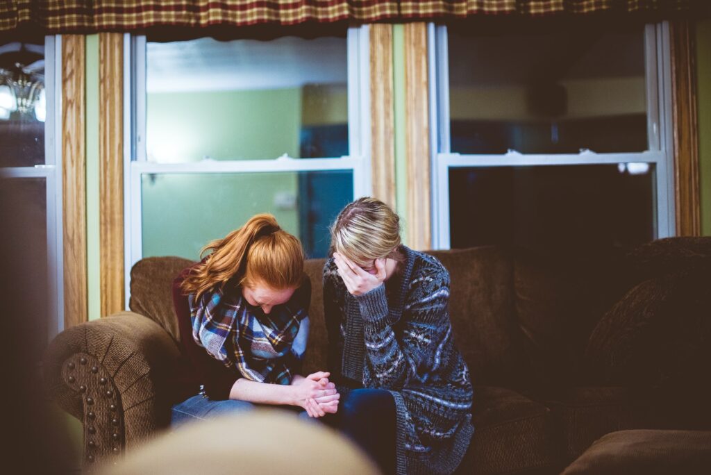 two women emotional and crying on sofa