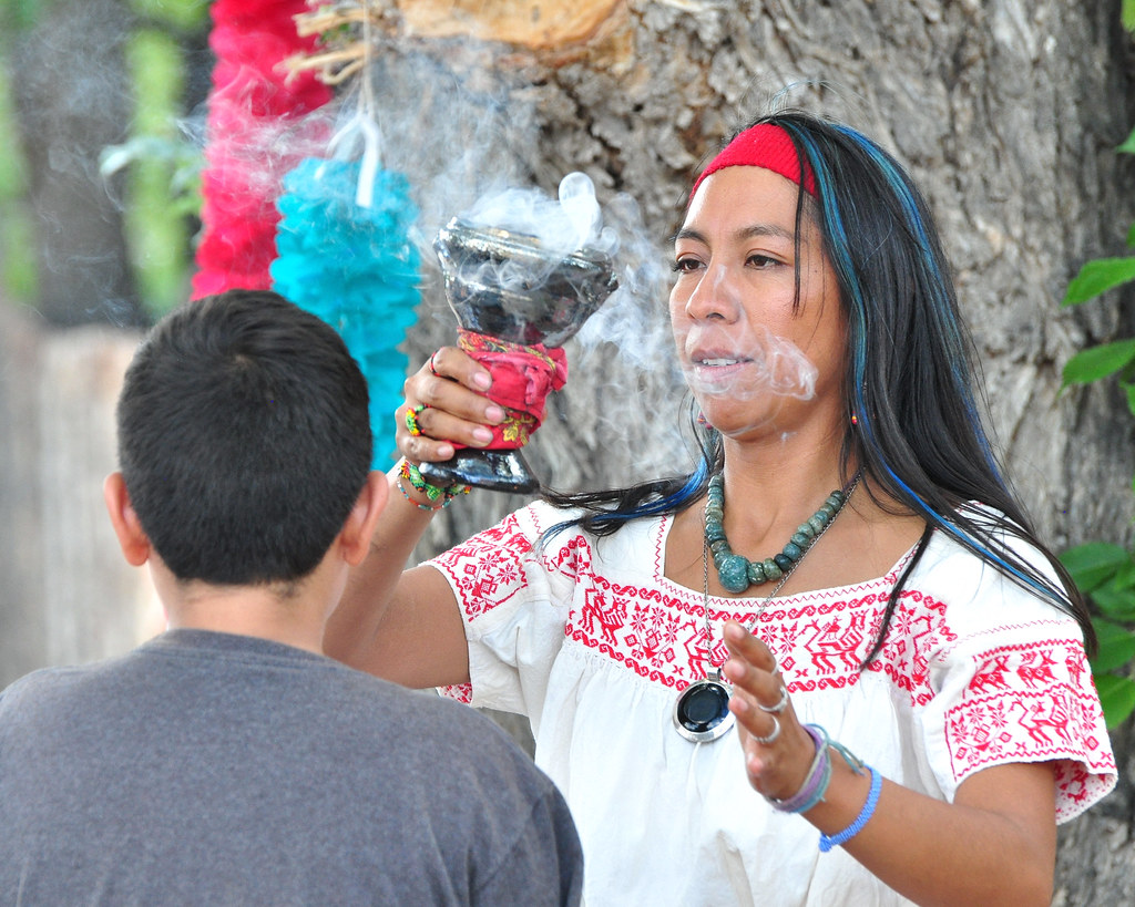 An indigenous healer holding a vessel with smoke emanating from it.