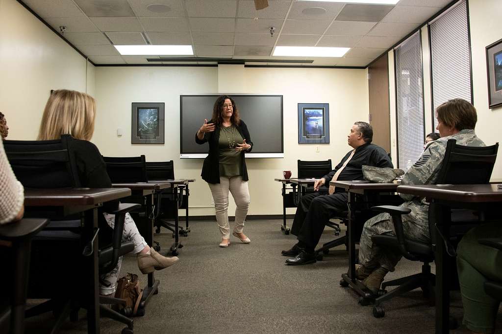 A woman standing in front of several employees providing training in an office.